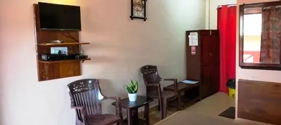 a room with a table and chairs and a tv at Holidayincoorg - Brick lane in Madikeri