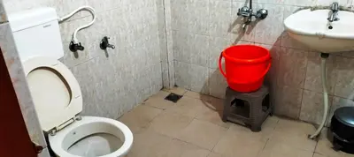 a bathroom with a toilet and a sink and a red bucket at Holidayincoorg - Brick lane in Madikeri