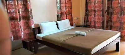 a bedroom with a bed with a chair and curtains at Holidayincoorg - Brick lane in Madikeri