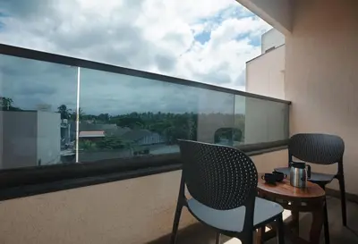 a balcony with two chairs and a table and a window at Apple Inn in Pollāchi