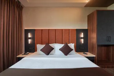 a bedroom with a large bed with white sheets and pillows at Apple Inn in Pollāchi