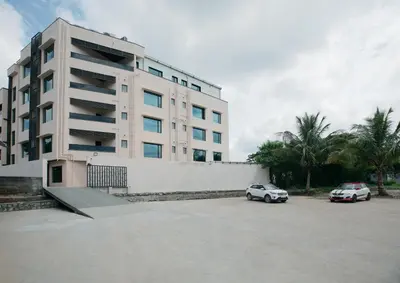two cars parked in a parking lot in front of a building at Apple Inn in Pollāchi