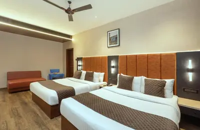 a hotel room with two beds and a chair at Apple Inn in Pollāchi