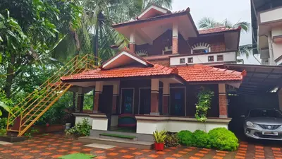 a house with a car parked in front of it at Nirmalyam Homestay in Kuttippuram