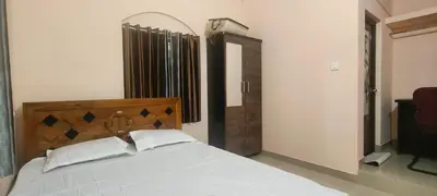 a bedroom with a white bed with a wooden headboard at Nirmalyam Homestay in Kuttippuram