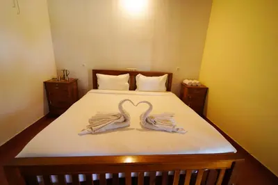 two swans towels on a bed in a room at Trogon resort in Kabini River