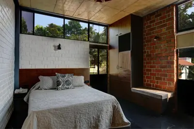 a bedroom with a bed and a brick wall at Vettaths in Kozhikode