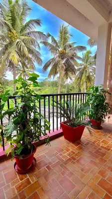 a balcony with palm trees and potted plants on it at Flintstone Home in Kushālnagar
