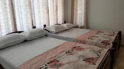 two beds sitting next to each other in a bedroom at Flintstone Home in Kushālnagar