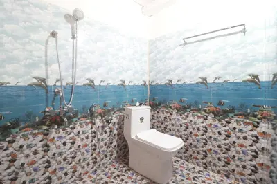 a bathroom with a toilet and a mural of birds at Flintstone Home in Kushālnagar