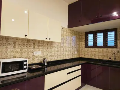 a kitchen with white cabinets and a microwave at Bricknest hillview in Mysore