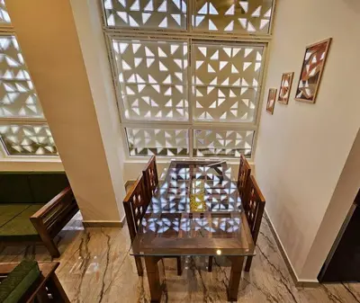 a wooden table with chairs in a room with a window at Bricknest hillview in Mysore