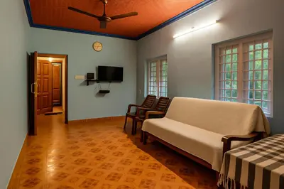 a living room with a couch and chairs and a tv at Evergreen Homestay in Kollengode