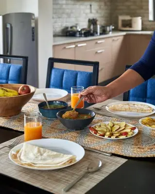 a person is preparing food on a table with plates of food at Shangrila Casa-Premium Homestay in Lovedale