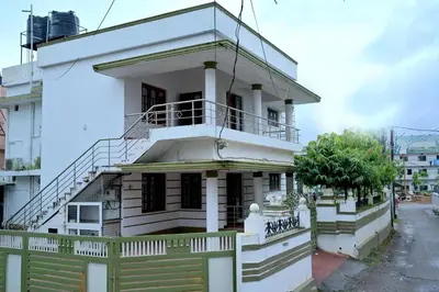 a white house with a balcony on a street at K K Gardens in Palakkad