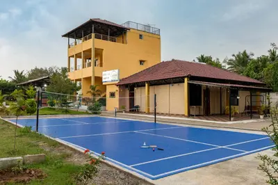 a tennis court in front of a building at Encanto Farmstay Resort in Mysore