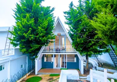 a small house with a balcony and trees at Cucuu Nest Villa Coonoor by VOYE HOMES - Surrounded by Tea Plantations in Coonoor
