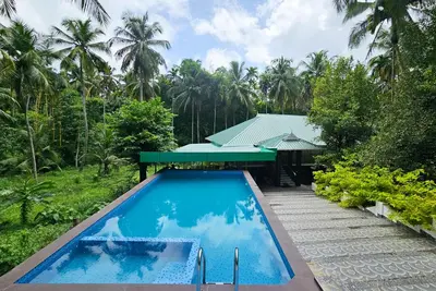 a swimming pool in front of a house at Nutmeg Farmstay with Pool, Vadakkencherry, Palakkad in Vadakkāncheri