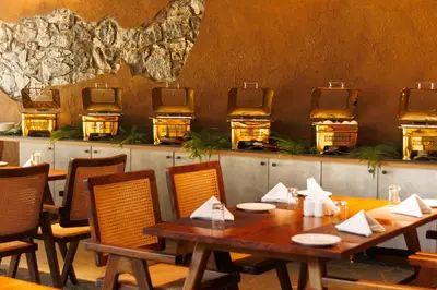 a dining room with a table and chairs and a wall at Jungle Park Resort-Rain Forest Experience by GreenEscapes in Vythiri