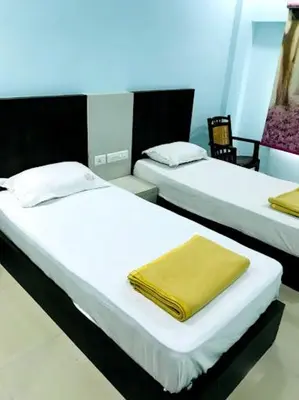 two beds in a room with a yellow towel on them at PLAZA RESIDENCY and CONFERENCE HALL in Malappuram