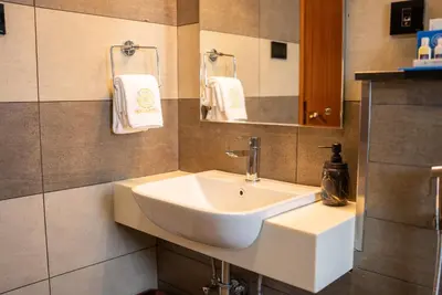a bathroom with a sink and a mirror and towels at Mazarine Hotels & Resorts LLP in Kalpetta