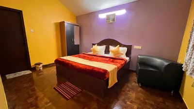a bedroom with a bed and a black leather chair at Mountain melody cottages in Ooty