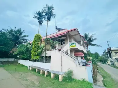 a man sitting on a porch of a house at GURI Homestay in Kushālnagar