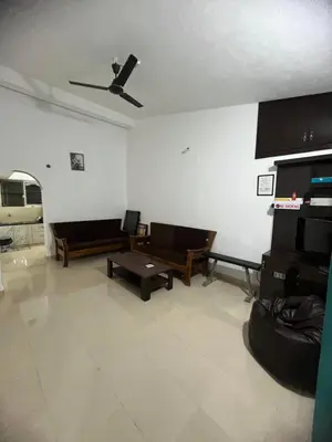 a living room with couches and a ceiling fan at GURI Homestay in Kushālnagar