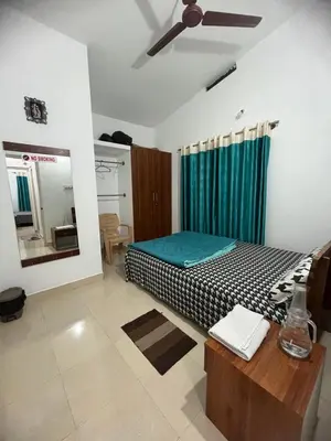a bedroom with a bed and a ceiling fan at GURI Homestay in Kushālnagar