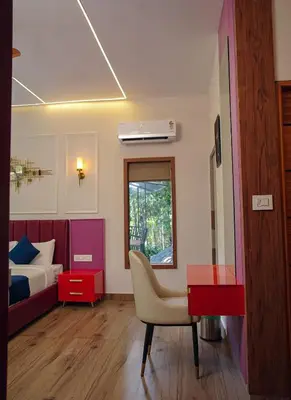 a bedroom with a bed and a desk and a chair at Hunters Hideout Resort in Wayanad