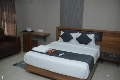 a bedroom with a large bed with a chair and a couch at Cruz Inn calicut in Kozhikode