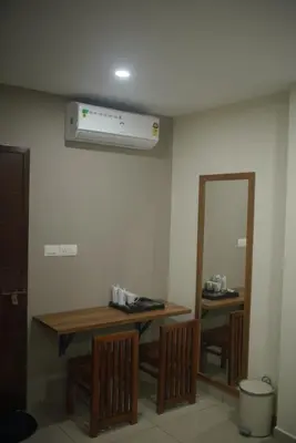 a dinning room with a table and a mirror at Cruz Inn calicut in Kozhikode