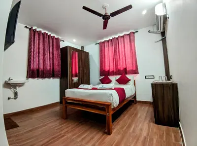 a bedroom with a bed with red curtains and a ceiling fan at Skyry Hotels Singanallur in Coimbatore