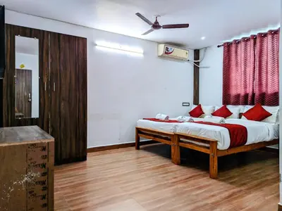 a bedroom with a bed with red pillows at Skyry Hotels Singanallur in Coimbatore