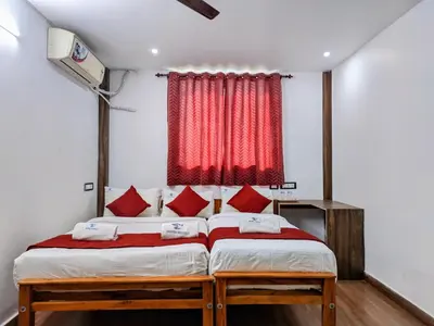 a bedroom with two beds and a red curtain at Skyry Hotels Singanallur in Coimbatore