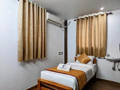 a small bedroom with a bed and a sink at Skyry Hotels Singanallur in Coimbatore