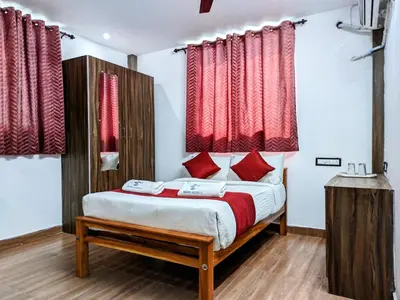a bedroom with a bed with red curtains at Skyry Hotels Singanallur in Coimbatore