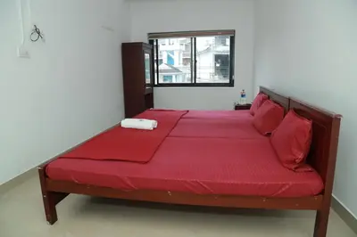 a large bed with red sheets and a window at Royal Park in Wayanad