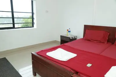 a bedroom with a bed with red sheets and a window at Royal Park in Wayanad
