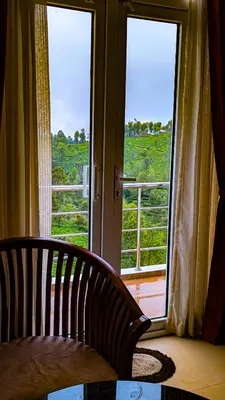 a chair in front of a window with a view at VALLEY VIEW INN, Kotagiri in Kotagiri