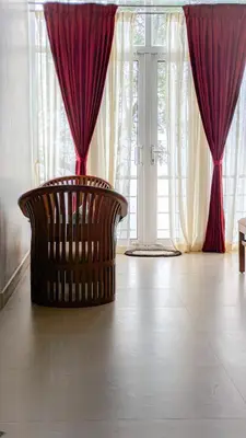 a room with red curtains and a chair in front of a window at VALLEY VIEW INN, Kotagiri in Kotagiri