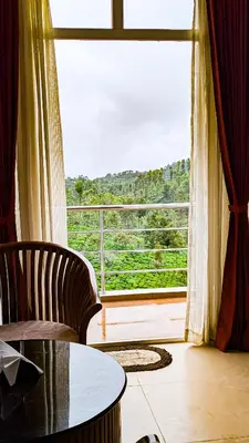 a room with a large window with a chair and a table at VALLEY VIEW INN, Kotagiri in Kotagiri
