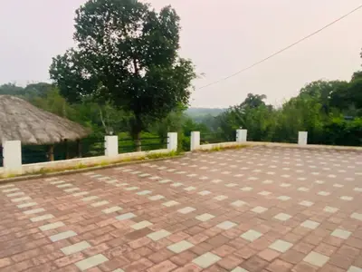 a brick parking lot with a tree in the background at Happydays Hut in Mananthavady