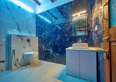 a bathroom with a toilet and a blue tiled wall at Shivvs Heritage Resort Ooty in Ooty