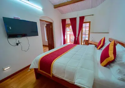 a bedroom with a large bed with a tv on the wall at Shivvs Heritage Resort Ooty in Ooty