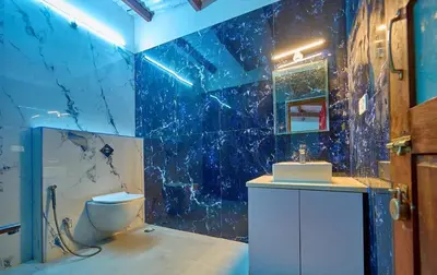 a blue tiled bathroom with a toilet and a sink at Shivvs Heritage Resort Ooty in Ooty