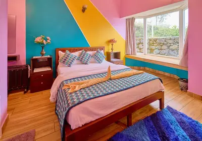 a bedroom with a bed with colorful walls and a window at EMYs Misty Charm Private Villa Ooty by VOYE HOMES in Ooty