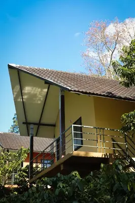 a yellow house with a balcony and a roof at The Rain Tree resort in Kutta