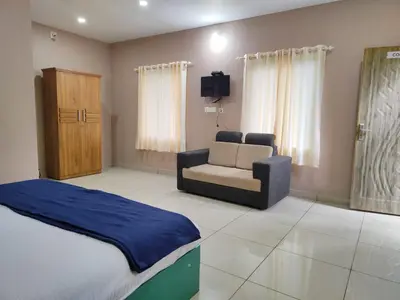 a bedroom with a bed and a couch and a chair at The Rain Tree resort in Kutta