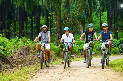 a group of men riding bikes down a dirt road at Palatty's Resorts in Athirappally